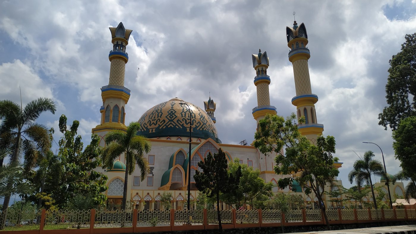 The Islamic Center in Mataram, Lombok: a patterned dome flanked by tall minarets against a cloudy sky.